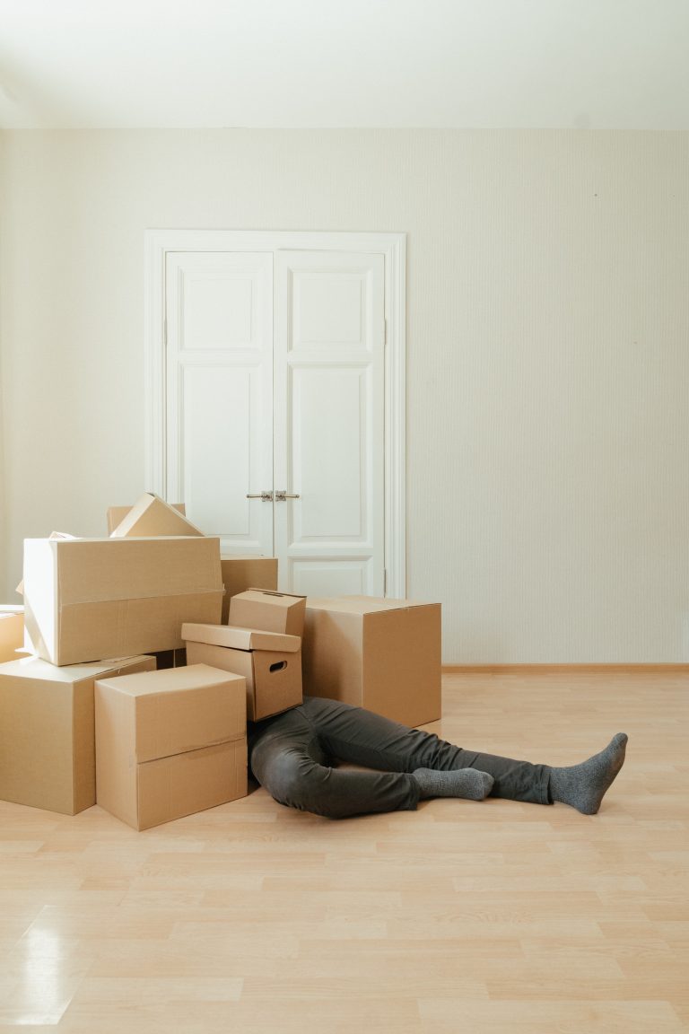 A marketer lies under a pile of boxes full of swag from cancelled events